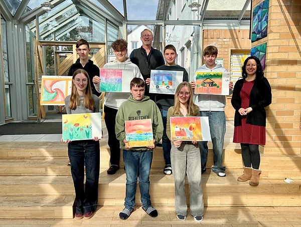 Schüler stehen mit ihren Kunstwerkwerken auf einer Treppe